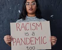 A girl holding a sign that says racism is also a pandemic.
